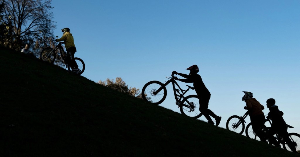 Cyclists pushing uphill together